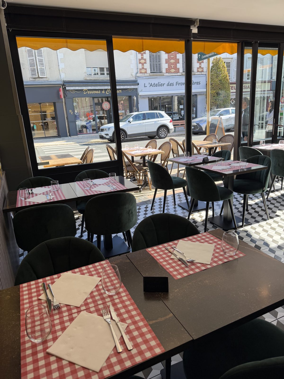 Tables dressées près des baies vitrées donnant sur la rue