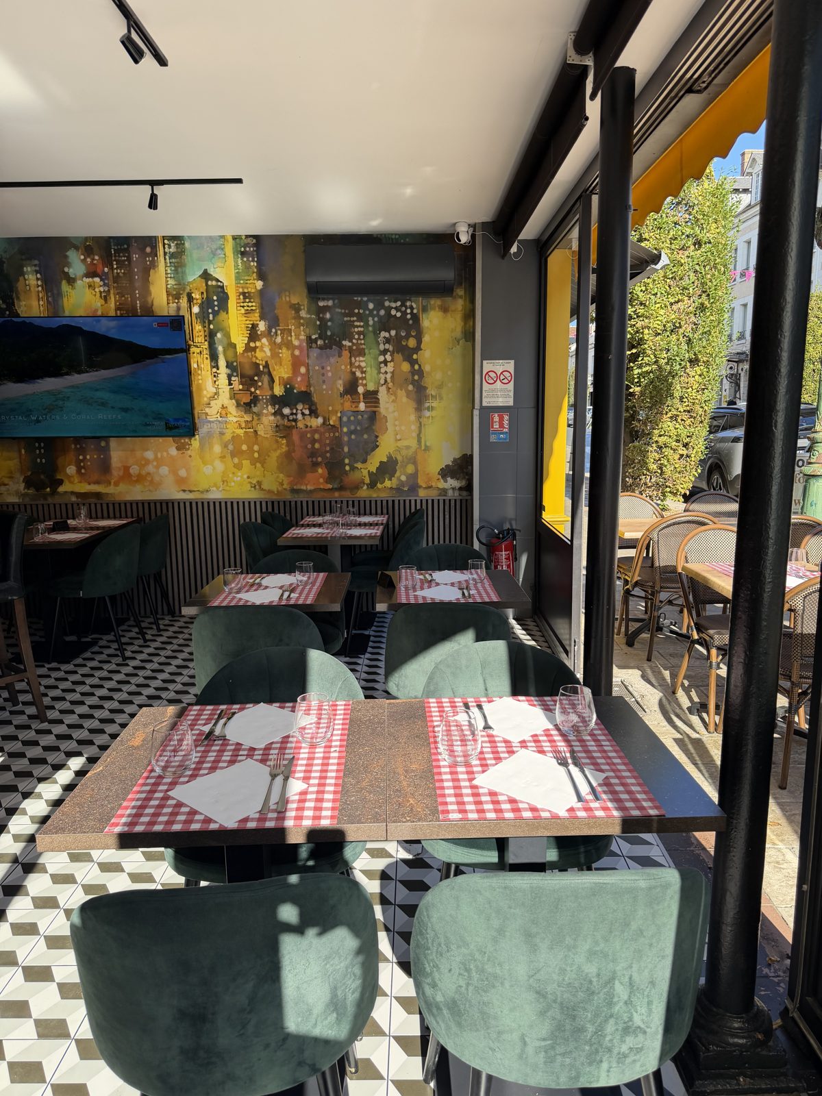 La salle du Cosy, tables à nappes à carreaux et grande fresque murale